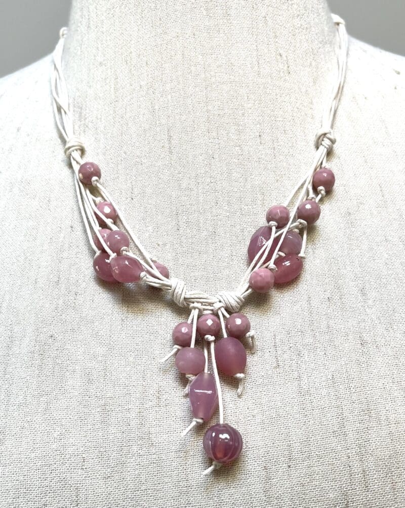 Variety of pink beads on fancy dangle necklace with cream string